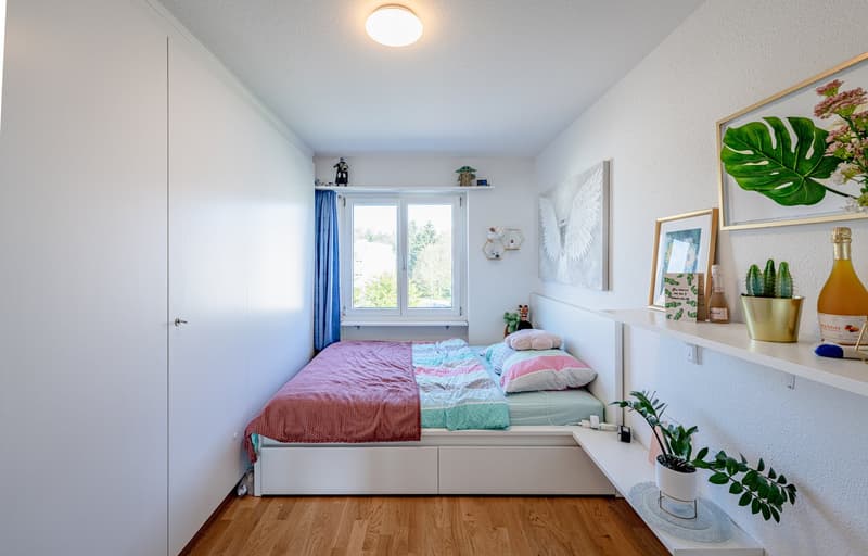 Bedroom with bed, window, shelves, plants, and decorations