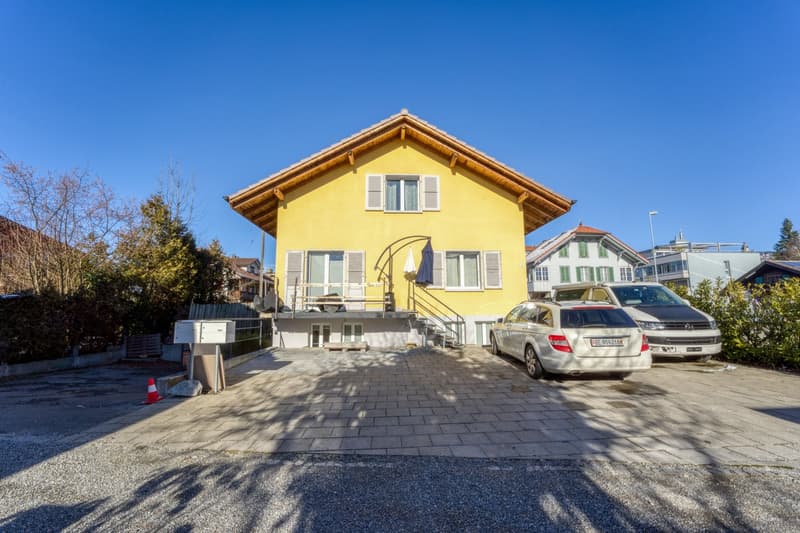 2-story yellow house, 3 cars parked, staircase and balcony on first floor, fenced garden