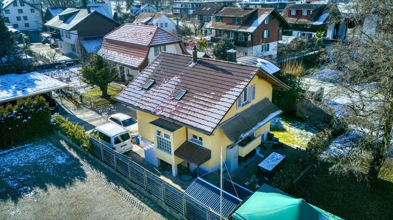 2 story house, brown roof, yellow walls, brown awning, garage with car, car parked in front of the house