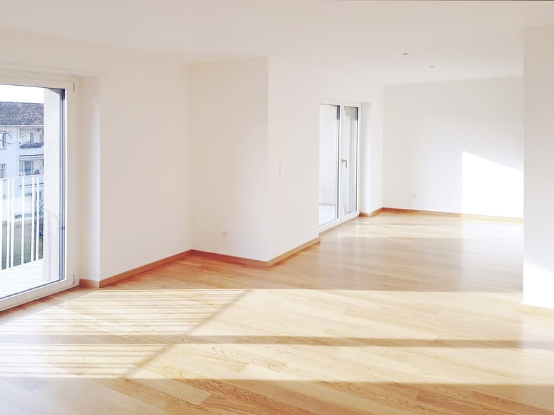 Empty room with wooden floors, white walls, glass doors, balcony with railing