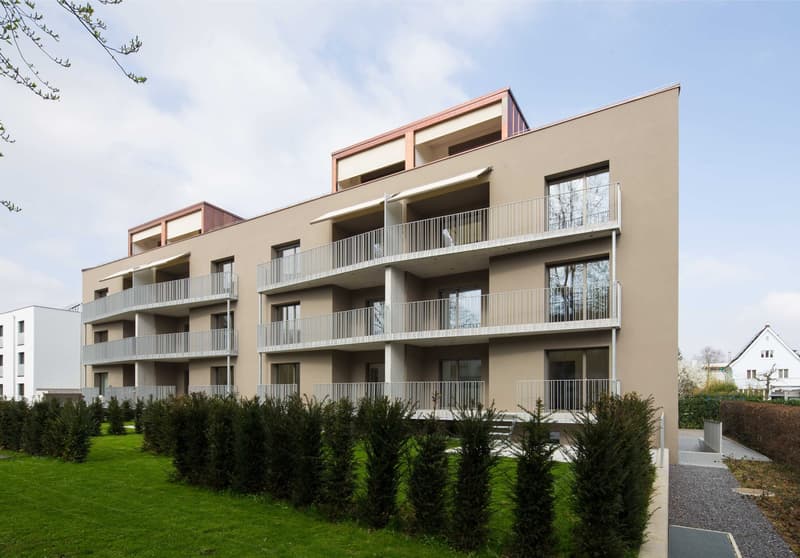 apartment building with multiple balconies and windows, concrete foundation, landscaped area