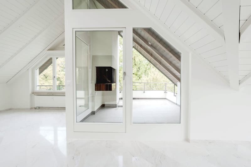 spacious attic room with white ceiling, glass doors leading to balcony, white marble floor, windows with balcony view
