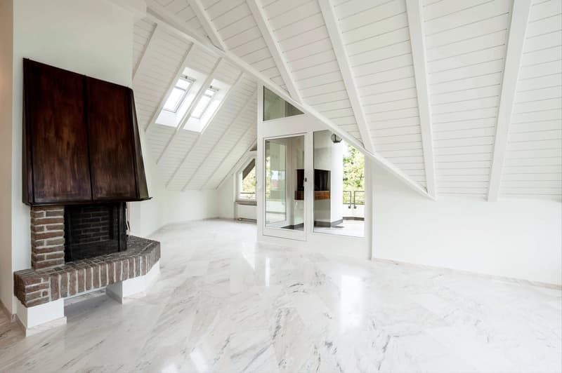 Empty room with marble floor, fireplace, glass door, slanted ceiling, skylights