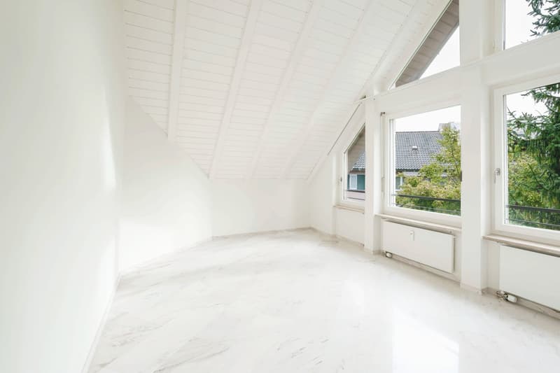 Empty room with white walls, white floors, three windows, wooden beams