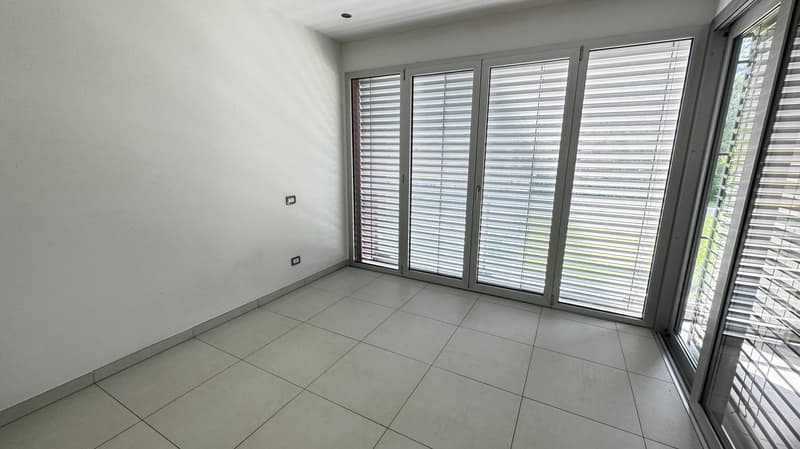white walls, tiled floor, three windows with shutters, one outlet on the wall