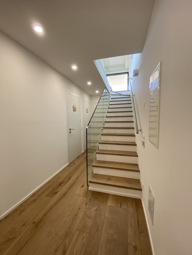 modern staircase with glass railings, wooden steps, white walls, wooden floor