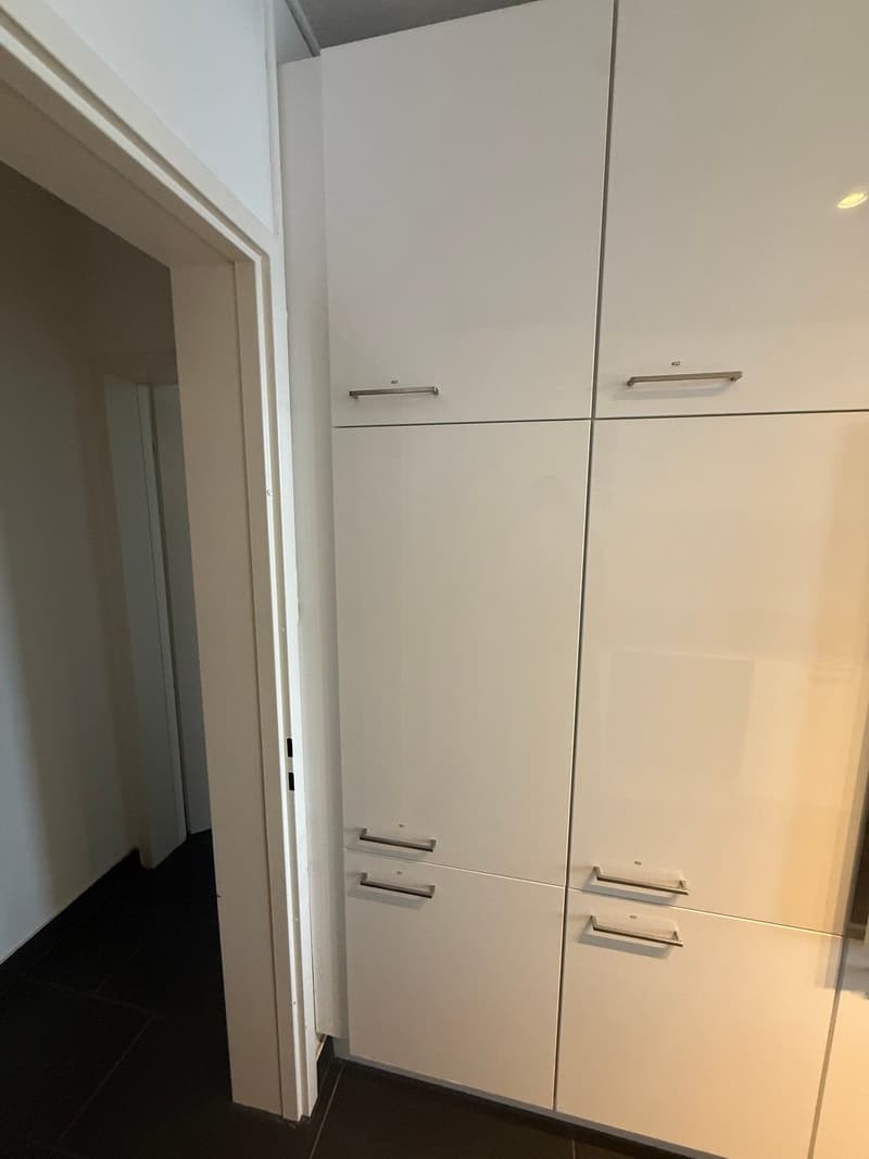 Wall mounted kitchen cabinets, hardwood floors, and a doorway