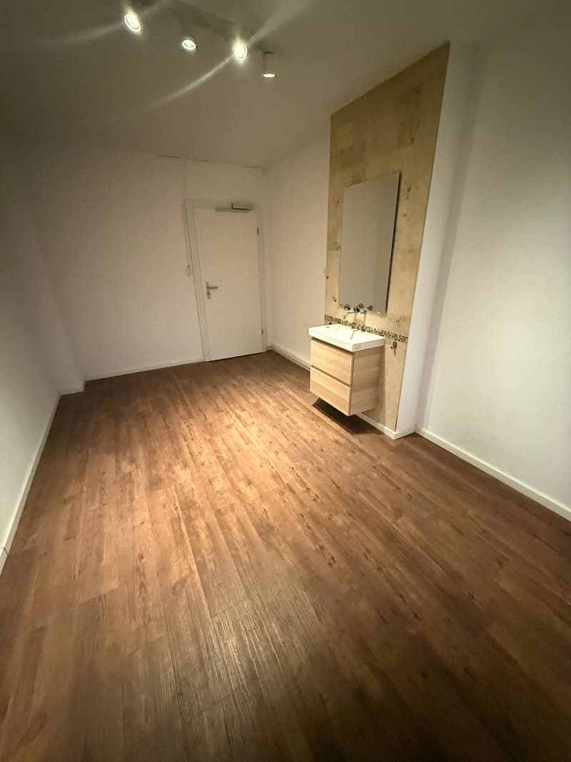 empty room, wooden floors, white walls, bathroom sink, mirror, open door, recessed lighting