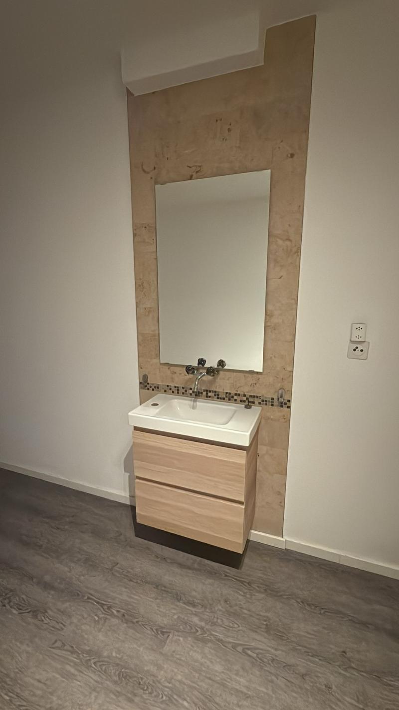 Bathroom with wooden cabinet, mirror, sink, and faucet.