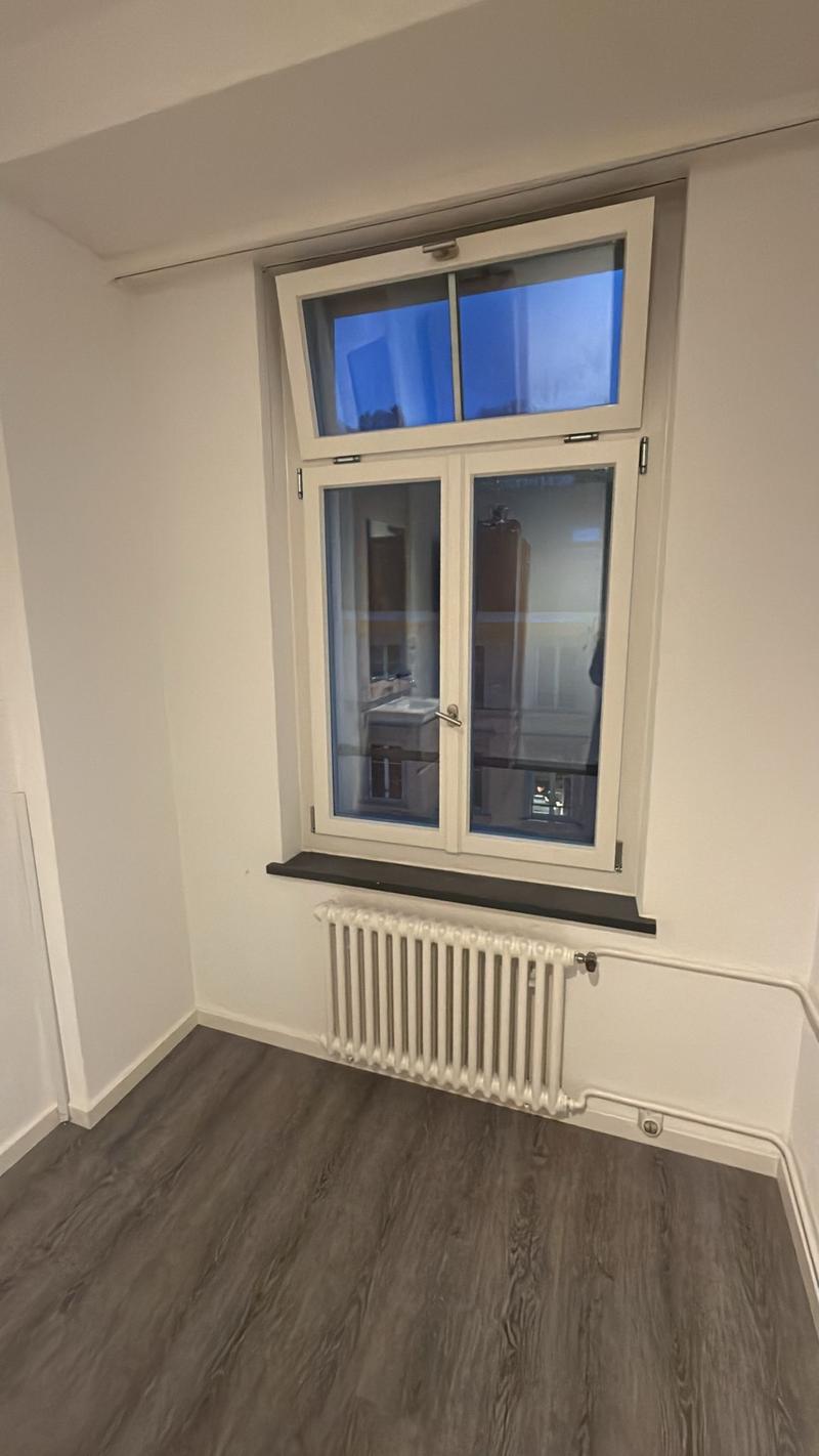 room with a window, radiator, wooden floor