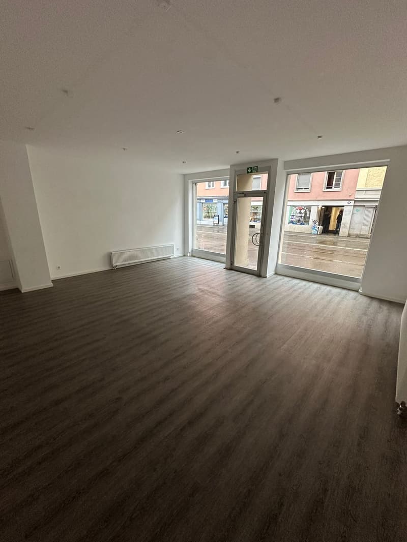 empty room, grey floor, white walls, 3 glass windows, a radiator