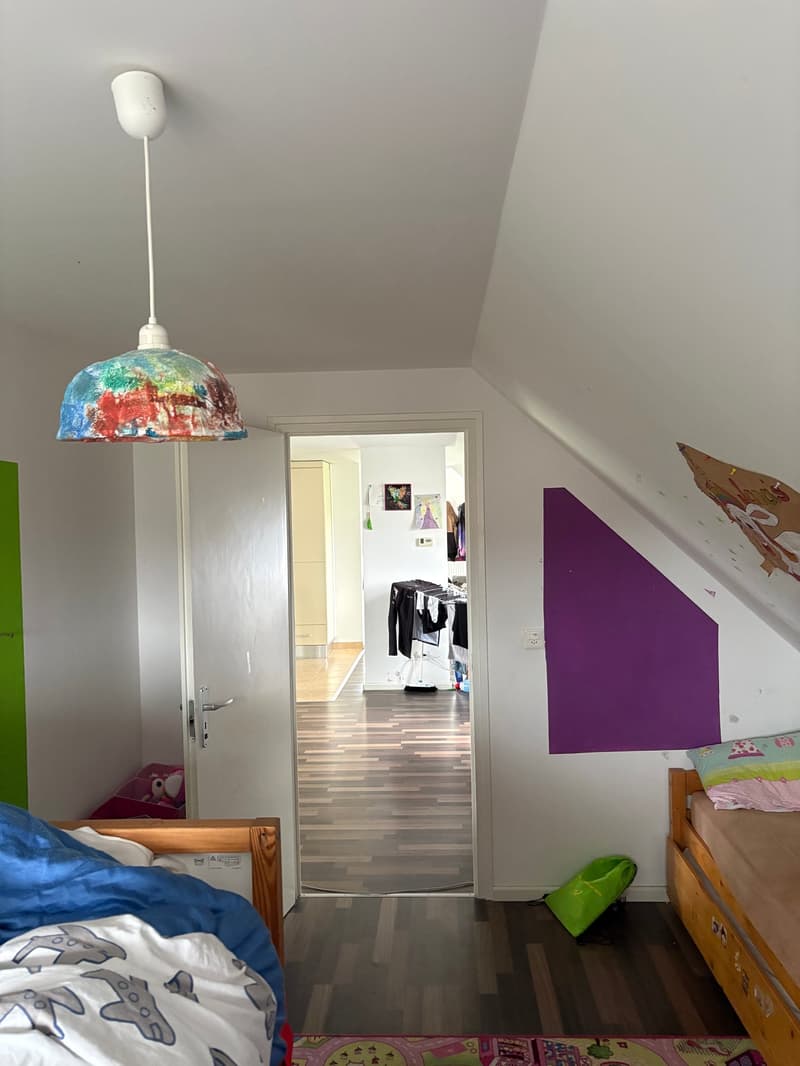 wooden floor, hanging lamp, two single beds, wardrobe, open door to hallway, pink rug, purple wall