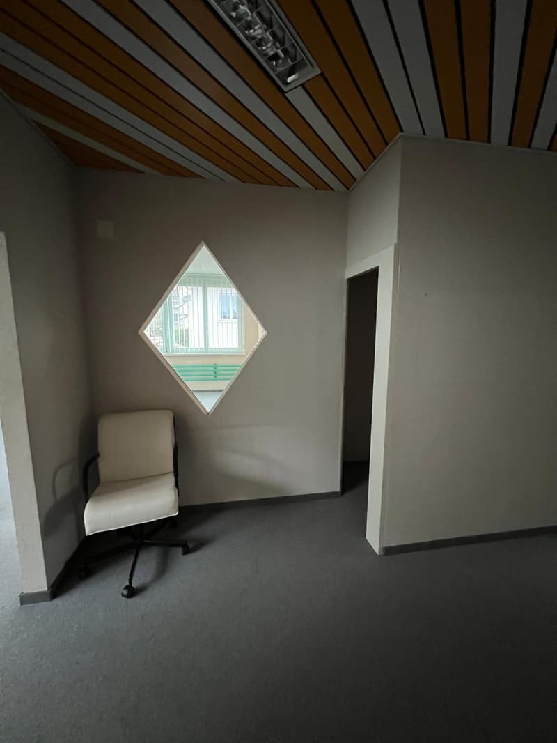 empty room, wooden wall, small chair, diamond-shaped window, gray carpet