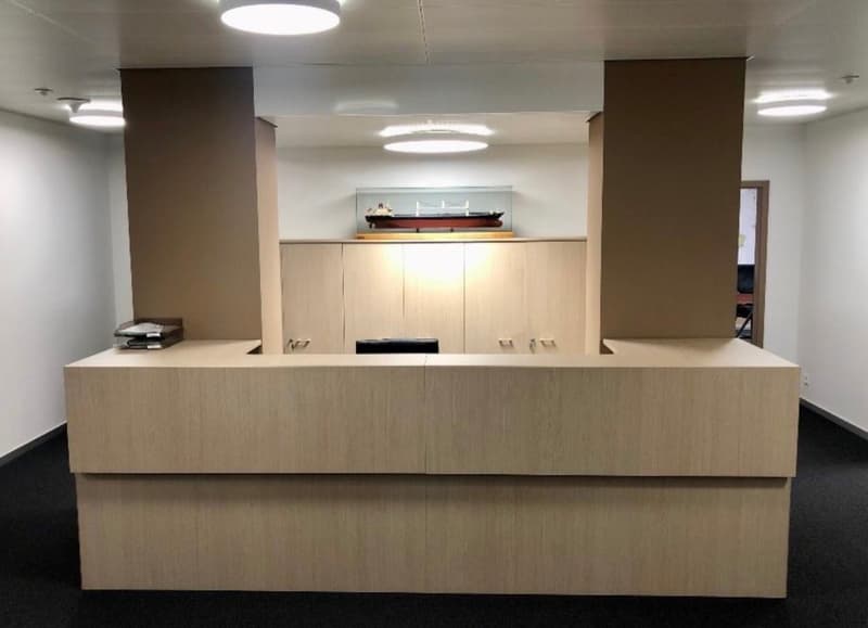 modern design with beige reception desk, wooden pillars, ceiling lamps, ship model on wall