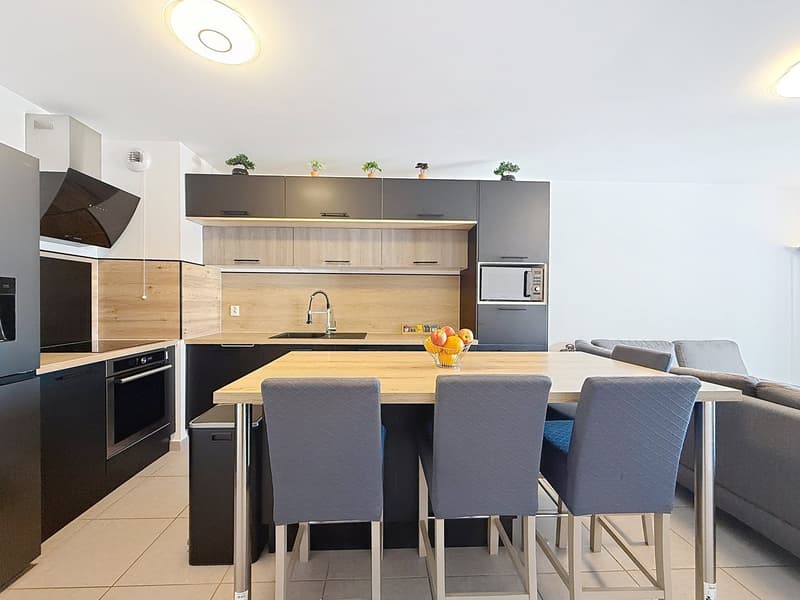modern kitchen with dining area, wooden countertops, black cabinets, stainless steel appliances, microwave, sink, faucet, dining table with chairs, couch, tiled floor