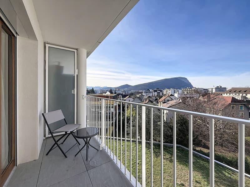 Balcony with a table and chair, metal railing, glass door, view of the city and mountains