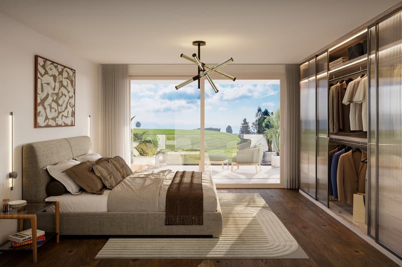 large bed with beige and brown bedspread, wooden headboard, two lamps, carpet, wardrobe with hanging clothes, large glass sliding door