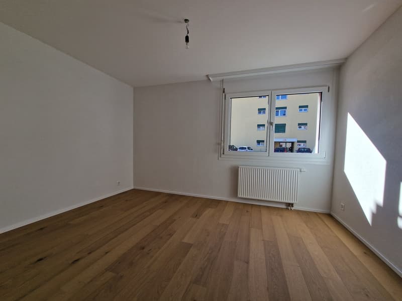 empty room, white walls, wooden floor, white radiator, window with view to street