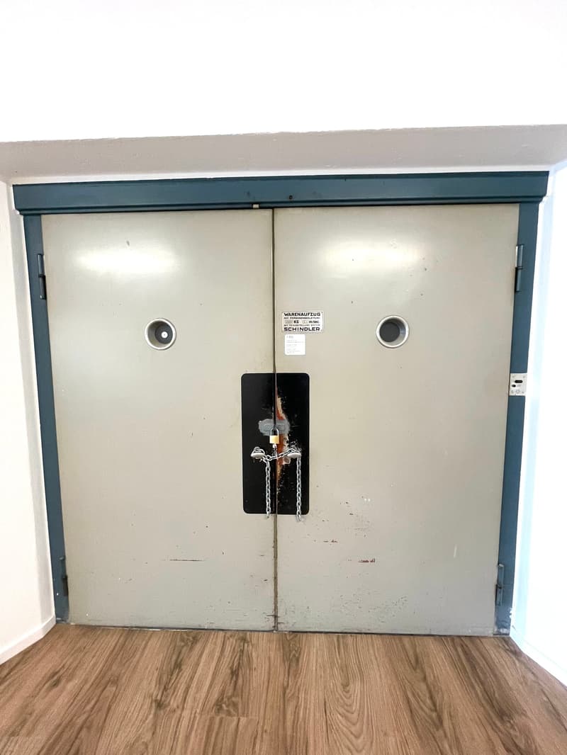 Grey door, with chain lock, wooden floor, white wall, blue border on top