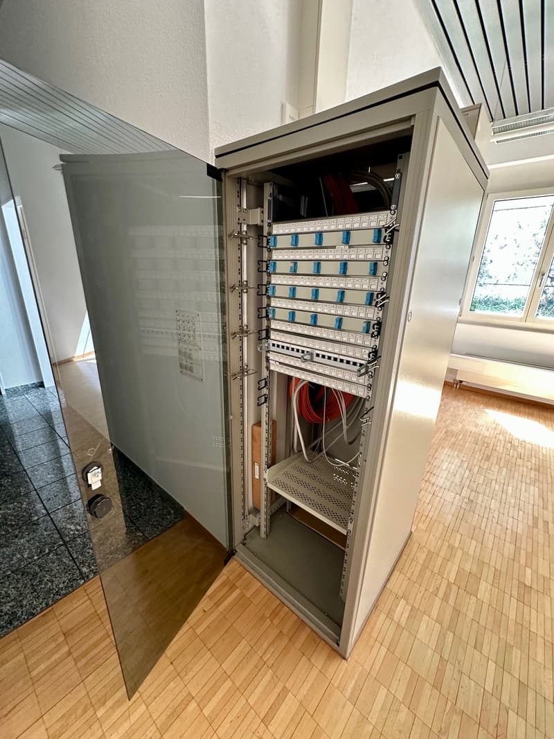 Opened server cabinet with many cables and switches
