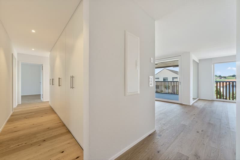 wooden floors, white walls, tall wardrobes, open sliding doors leading to balcony