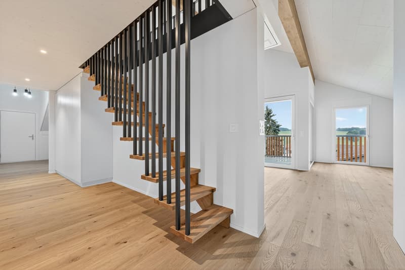 Open floor plan with modern staircase, hardwood floors, large glass doors leading to balcony