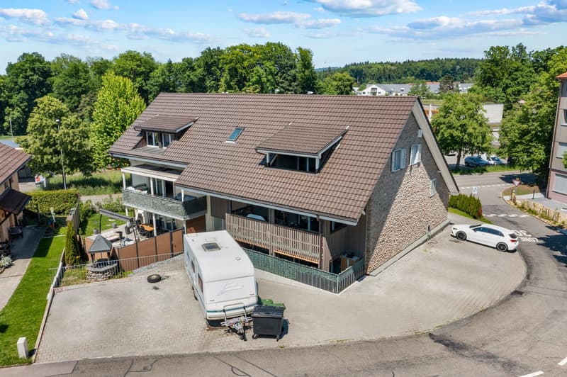 2 story house, brown roof, stone wall, car parked, attached garage, balcony, trailer