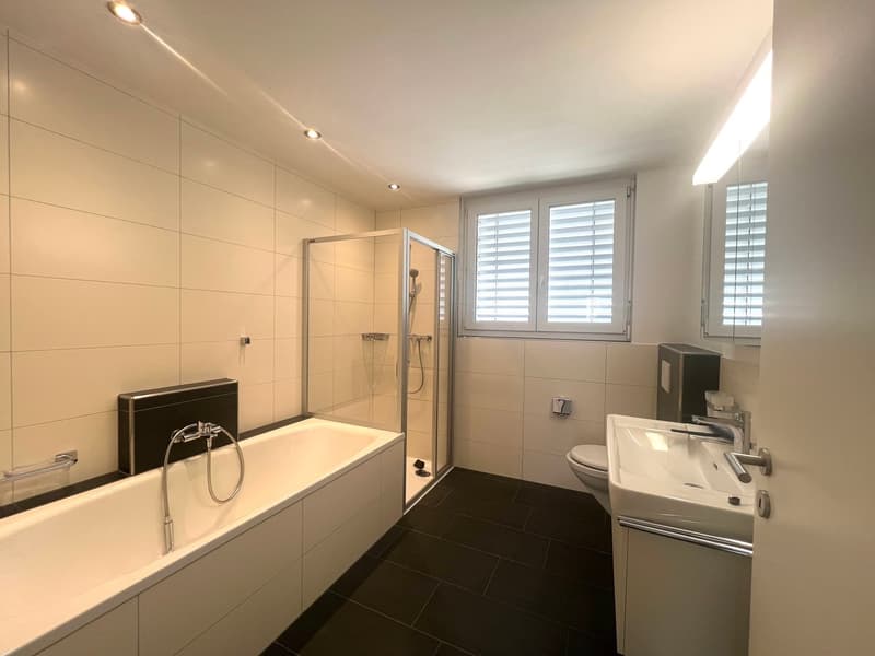 modern bathroom with bathtub, shower, toilet, sink, and white tiles