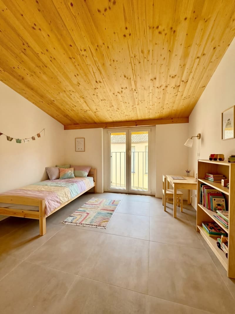 Bedroom with bed, rug, desk, chair, bookshelf, lamp, picture frame, and balcony