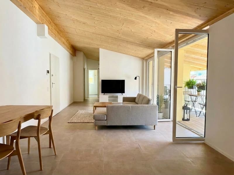modern living room with wooden table, gray sofa, flatscreen TV, beige rug, wooden ceiling