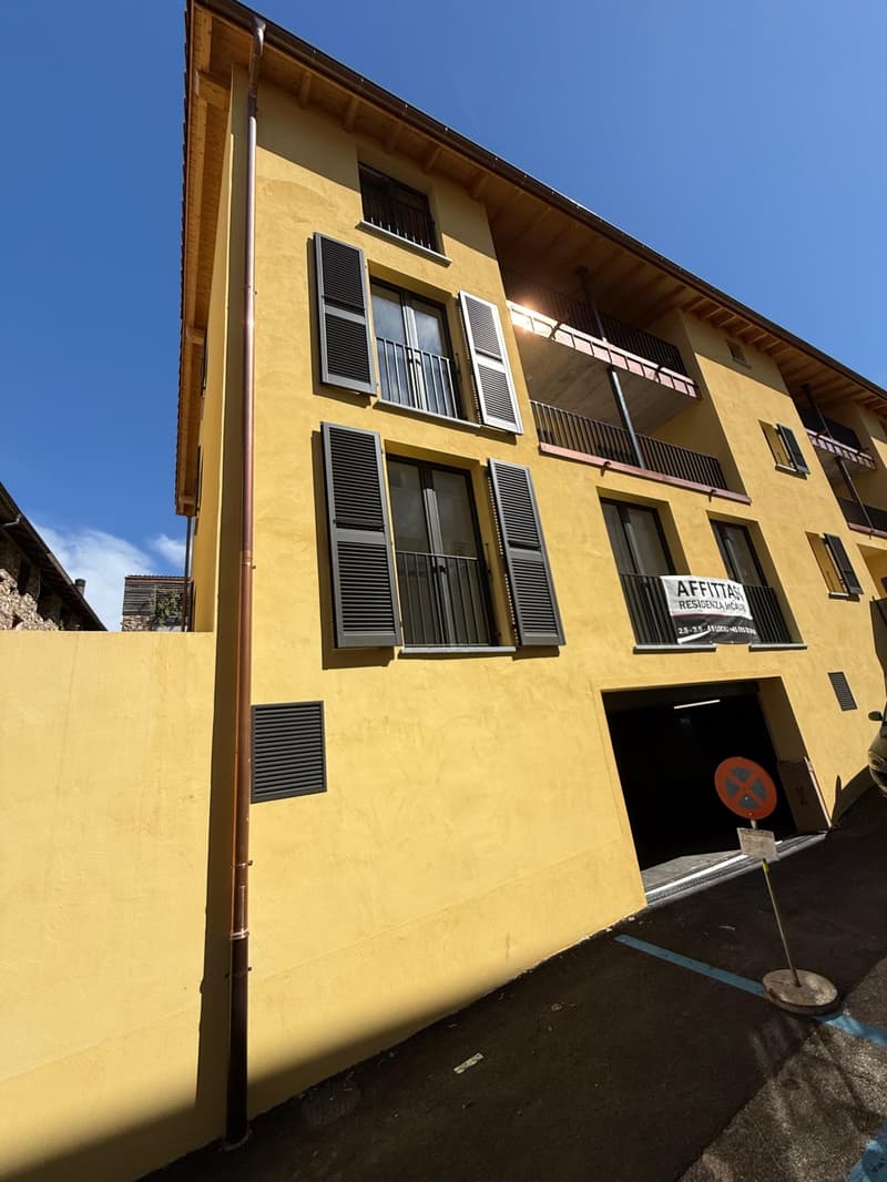 yellow building with balconies, metal shutters, and a garage entrance