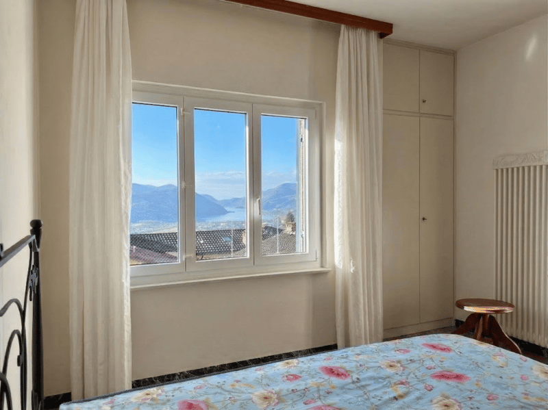 bedroom with bed, window with view, white curtains, wooden stool, wardrobe