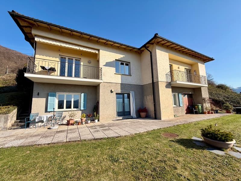 2 story house, beige exterior, blue shutters, 2 balconies, garden, patio with table and chairs