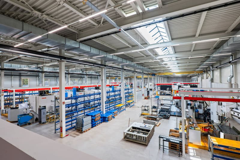 Factory layout with high ceilings, metal beams, racks, and various machines and equipment