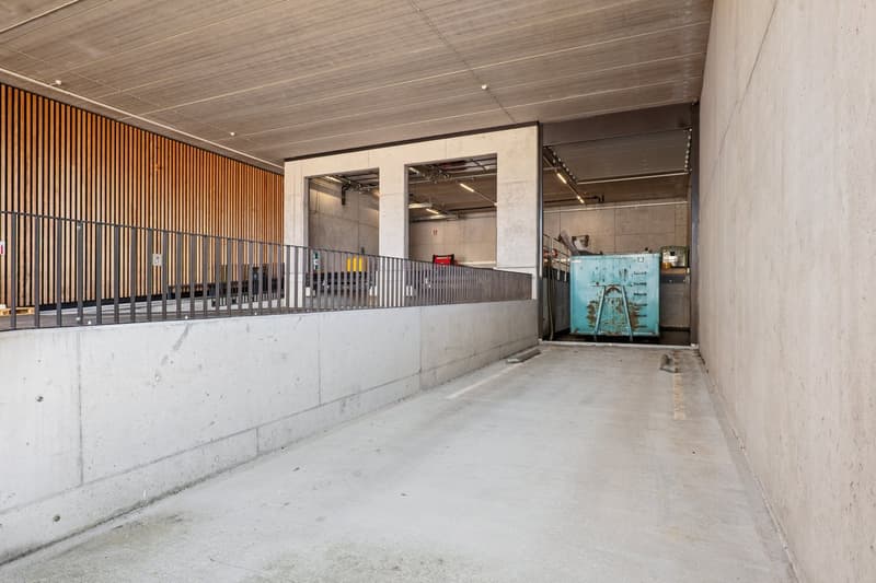 Metal railings, concrete walls, illuminated ceiling, multiple parking spots