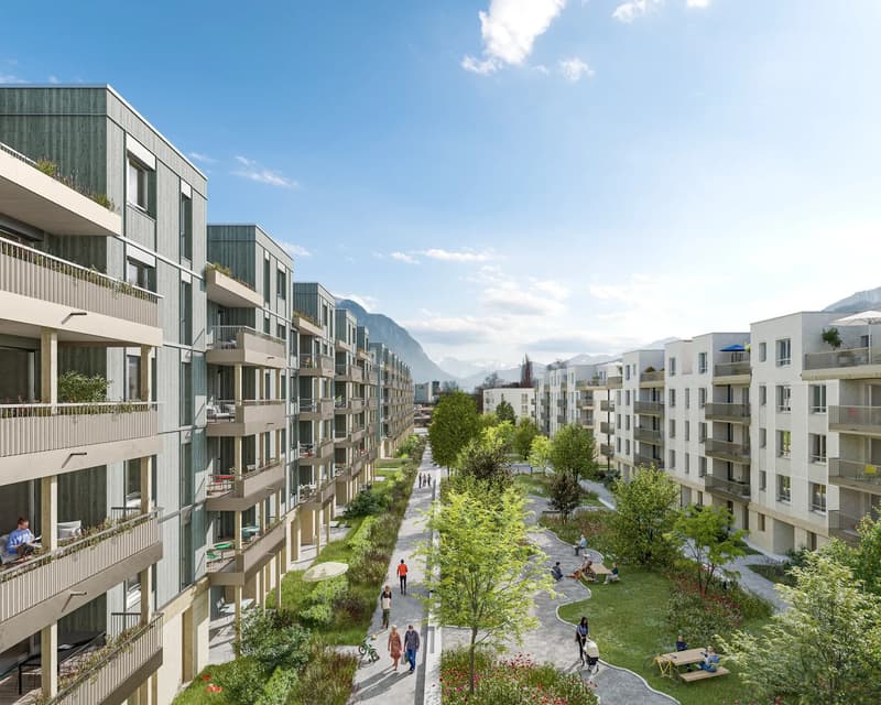 multistory apartment buildings, balconies, grassy park, paved pathway, mountains in the distance