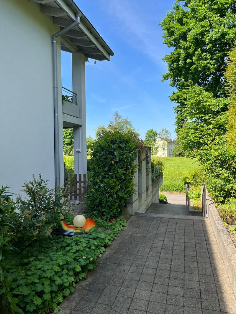 Raised ground floor house, brick wall, stone walkway, greenery