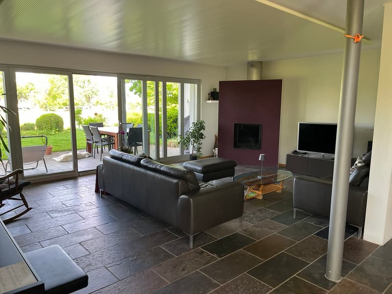 modern living room with sliding glass doors, black leather sofa, wooden coffee table, flat screen TV, TV stand, glass top, sliding glass doors to a patio, garden view