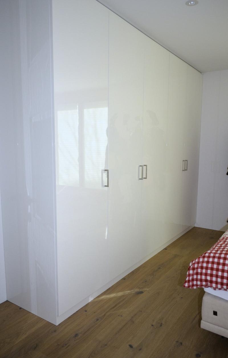 white wardrobes, wooden floor, white walls, window with blinds