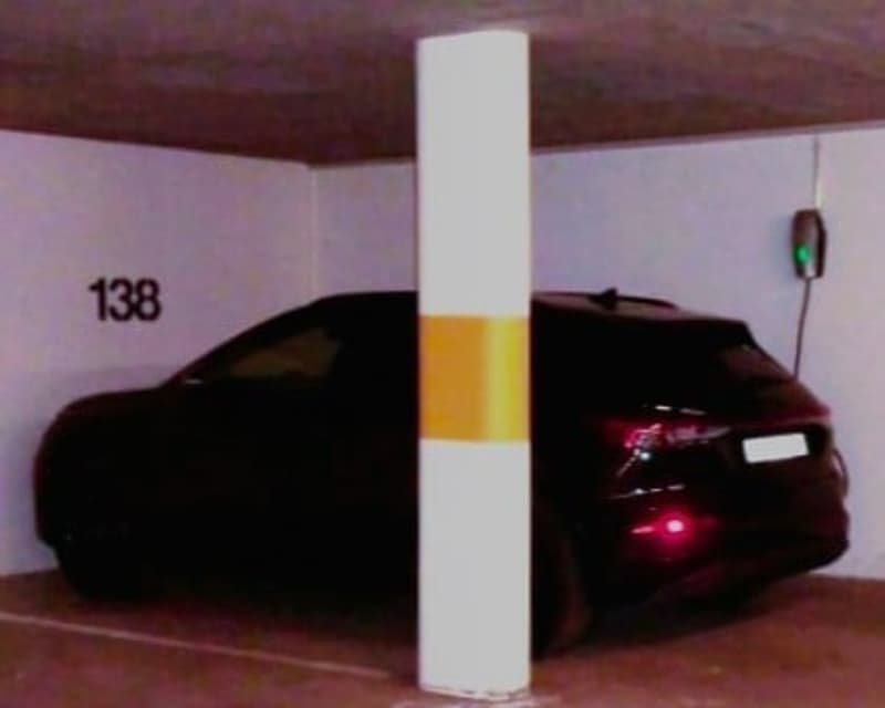Parking space number 138, black car parked, white and yellow column, charging station