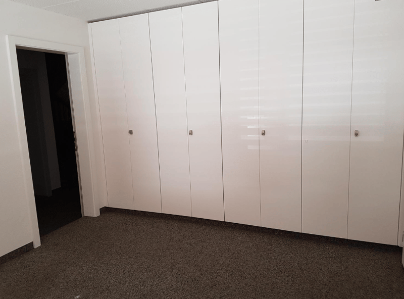 A large closet area with six white built-in cabinets.