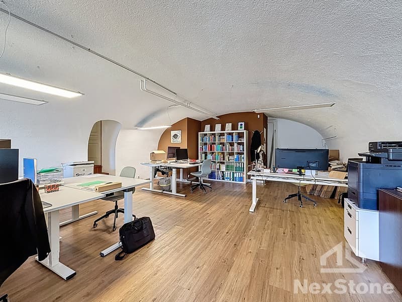 modern office with wooden floors, white walls, multiple desks, chairs, bookshelves, computer monitors, printers, and storage boxes