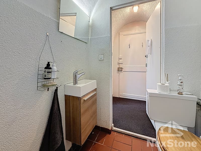 Bathroom with sink, mirror, towel rack, toilet, and a door leading to another room