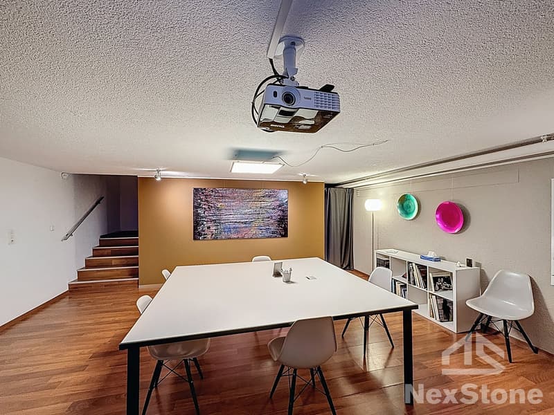 conference room with a long table, chairs, projector, bookshelves, and decorative items
