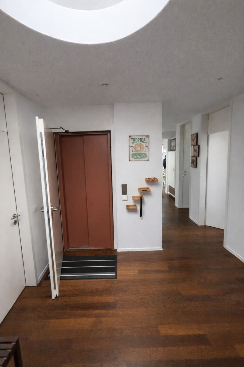 wooden floor, white walls, open door, shelves, sign, black mat
