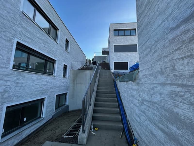 Modern building with concrete walls, glass windows, and a staircase leading to the upper floor.