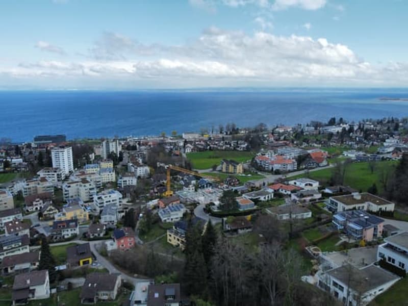 Aerial view of a town with many buildings, a crane, and a sea in the distance