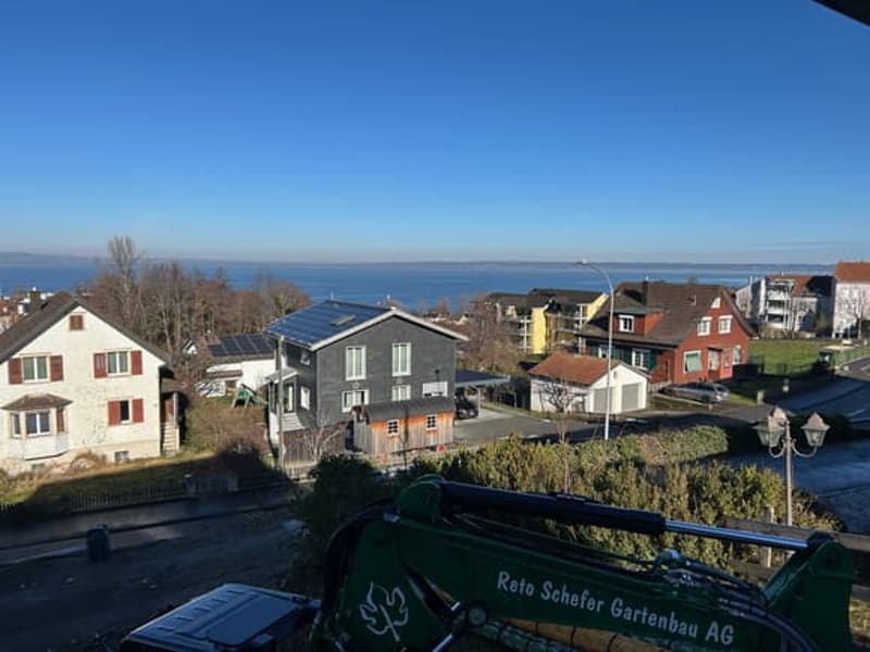 Houses in a row, one with solar panels, view of the sea, machinery in the foreground