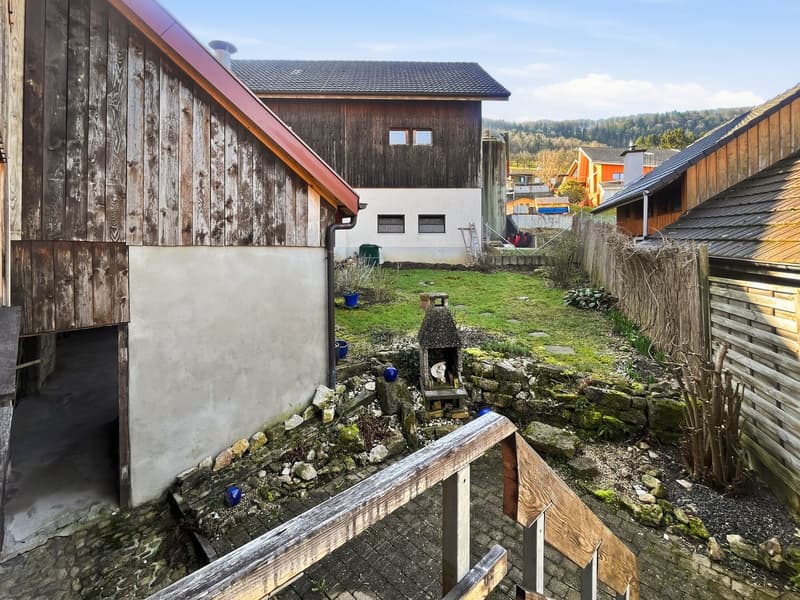 wooden buildings, stone walls, outdoor fireplace, green lawn, stone pathway, gravel