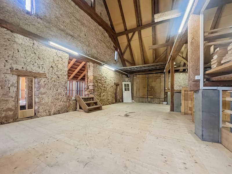 ample room with wooden beams and stone walls, wooden stairs, wooden storage shelves, wooden door, small wooden window